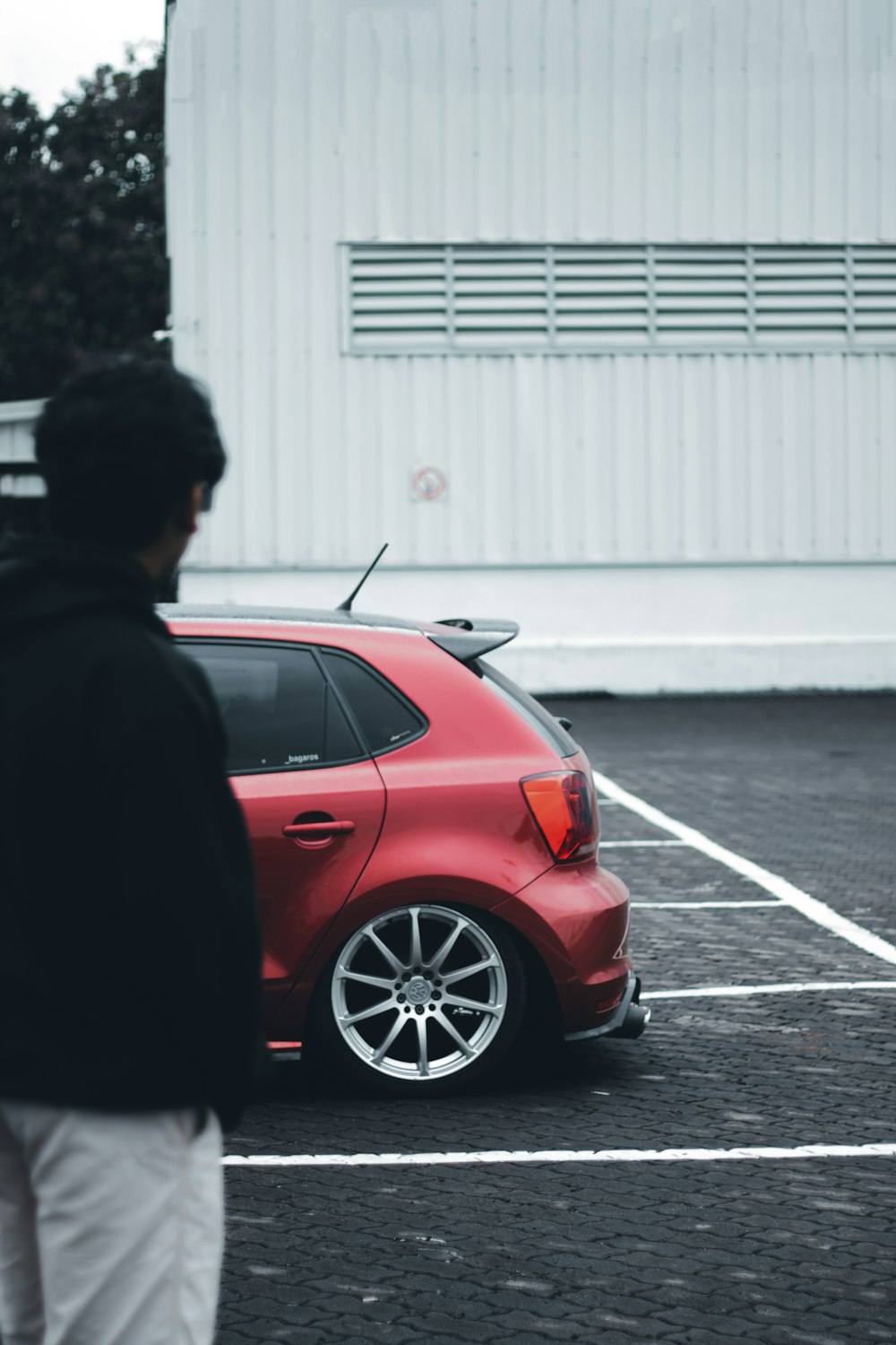 a man standing next to a red car