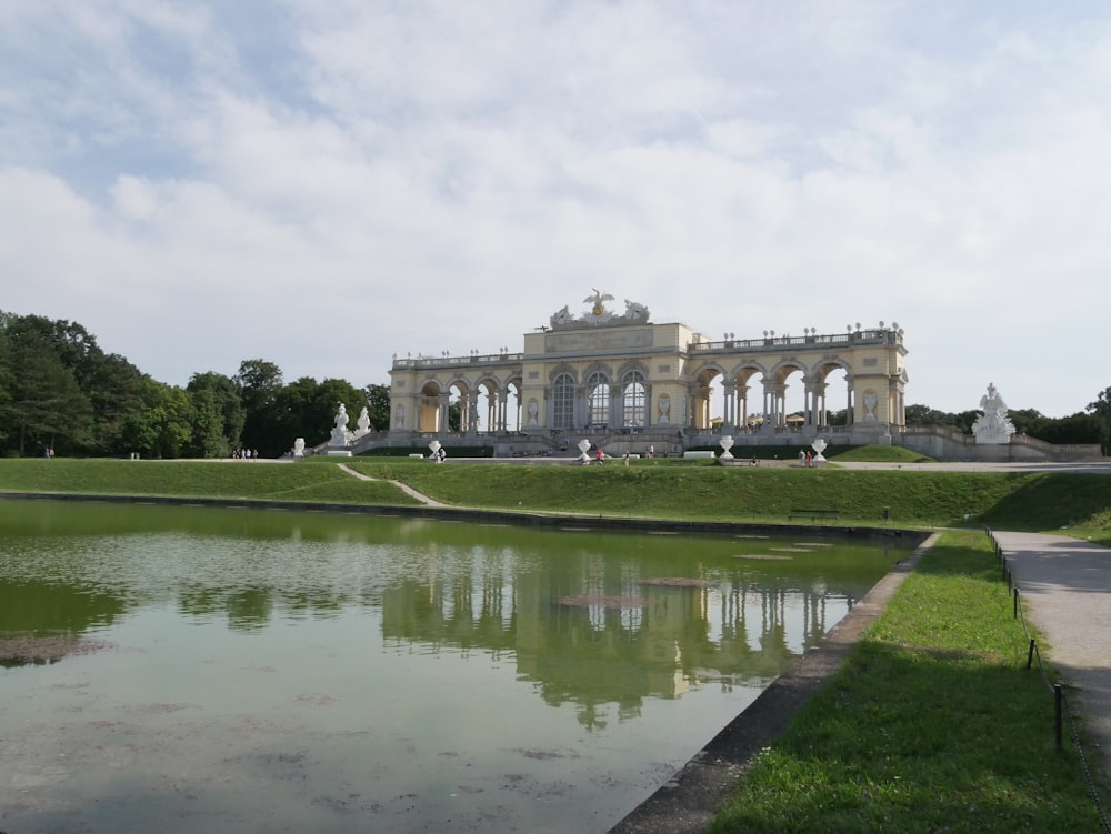 ein großes Gebäude mit einem Teich davor