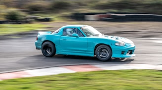 Dynamic shot of a blue BMW M2 accelerating on a racetrack, with motion blur.