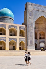 a man and woman posing in front of a large building