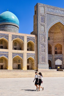 a man and woman posing in front of a large building
