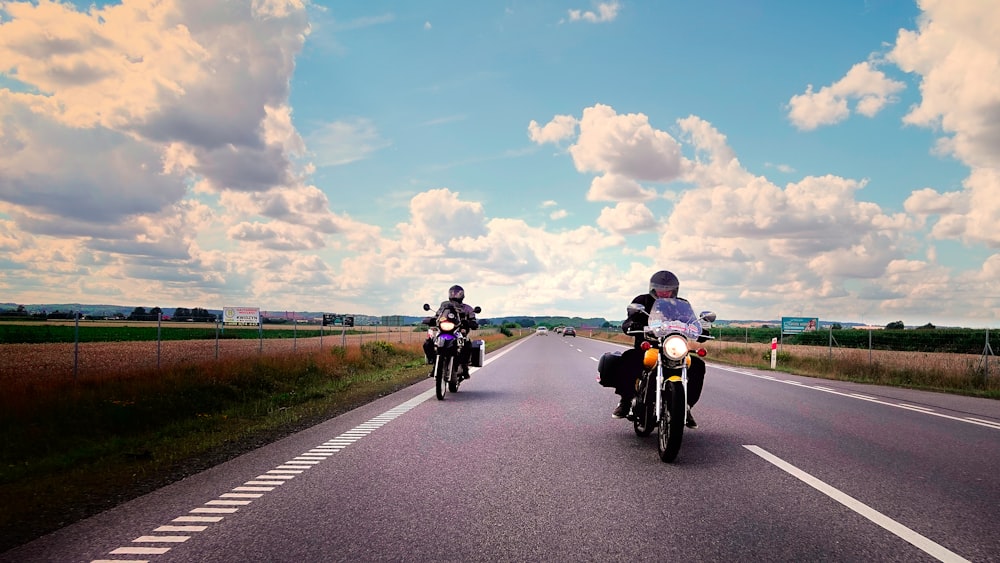 a couple of people ride motorcycles down a road