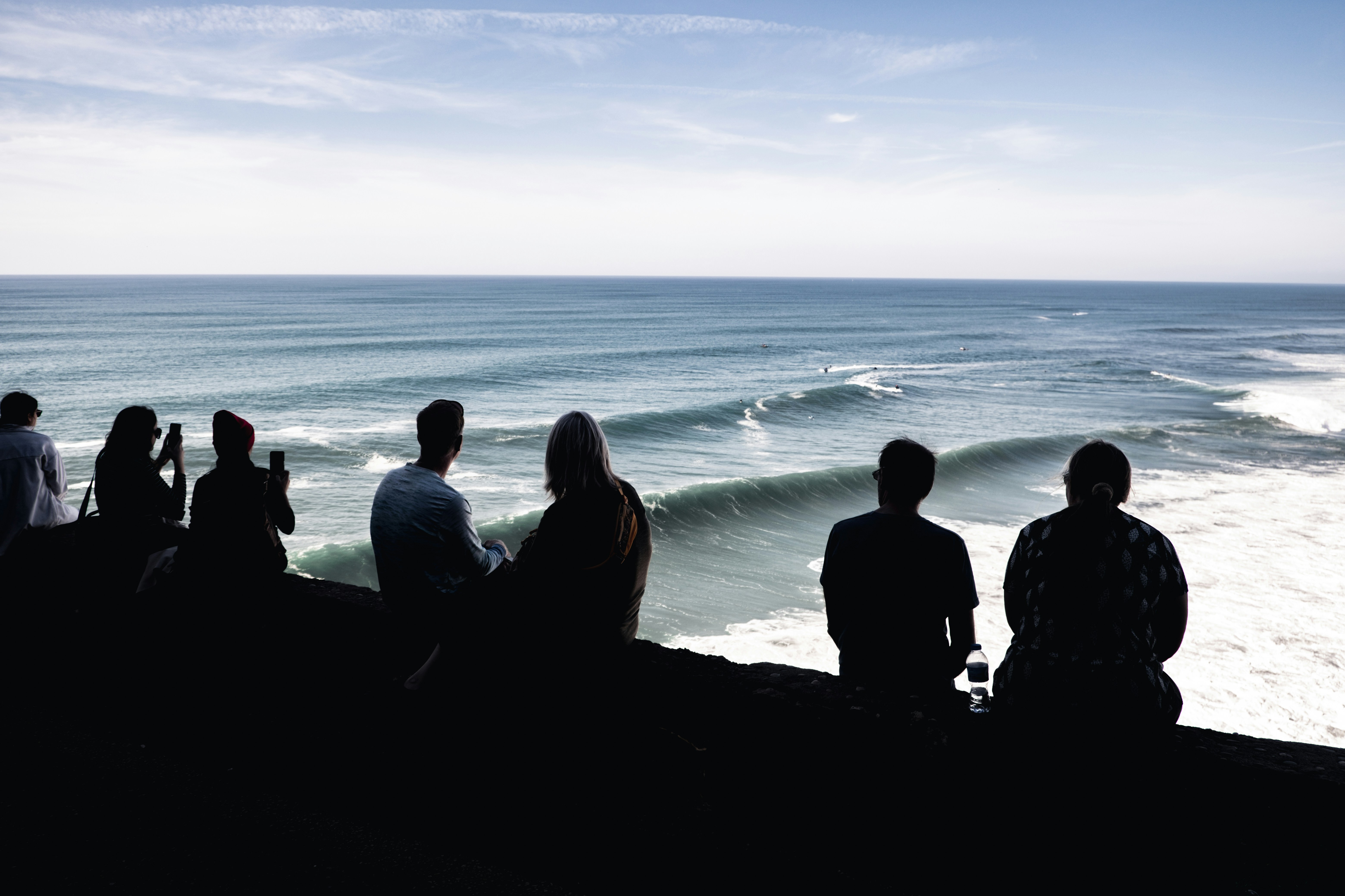 a group of people sitting on a beach looking at the ocean, Big wave season