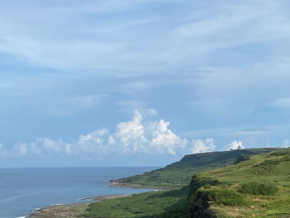 a beach with green hills and a body of water