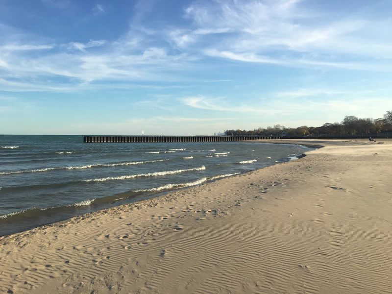 a beach with waves and a pier