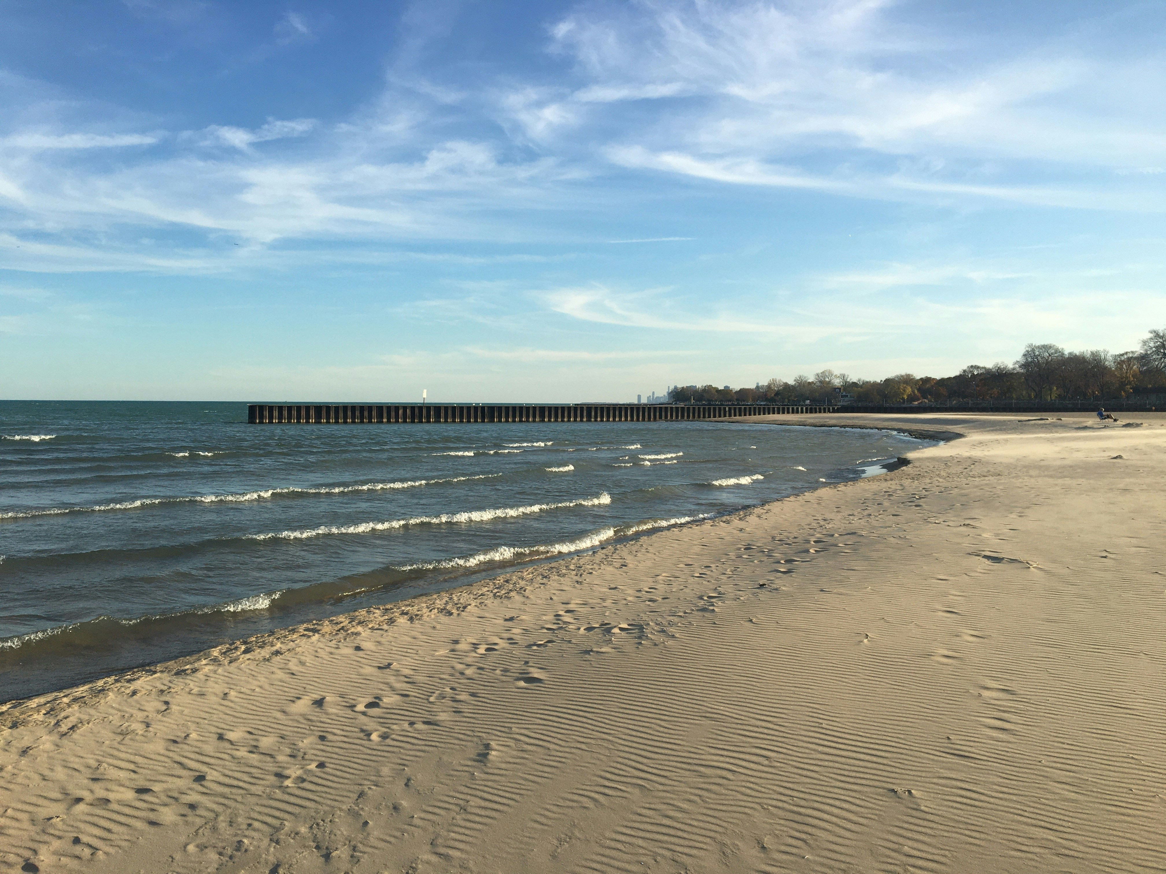 a beach with waves and a pier