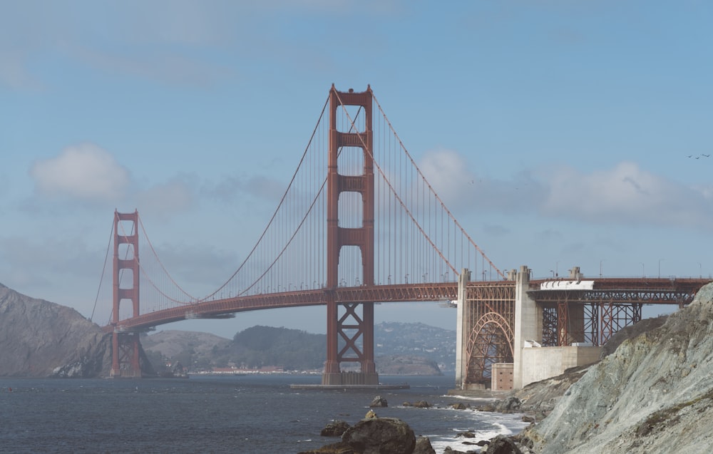 a large red bridge over water with Golden Gate Bridge in the background