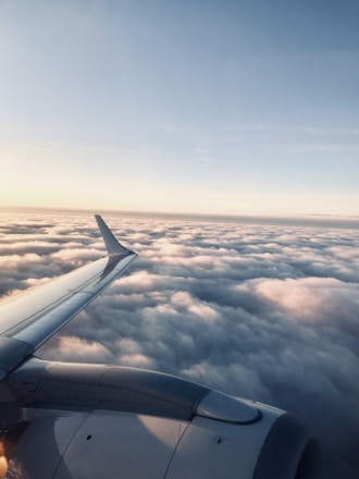 A sleek Boeing aircraft soaring above the clouds with a clear blue sky backdrop.