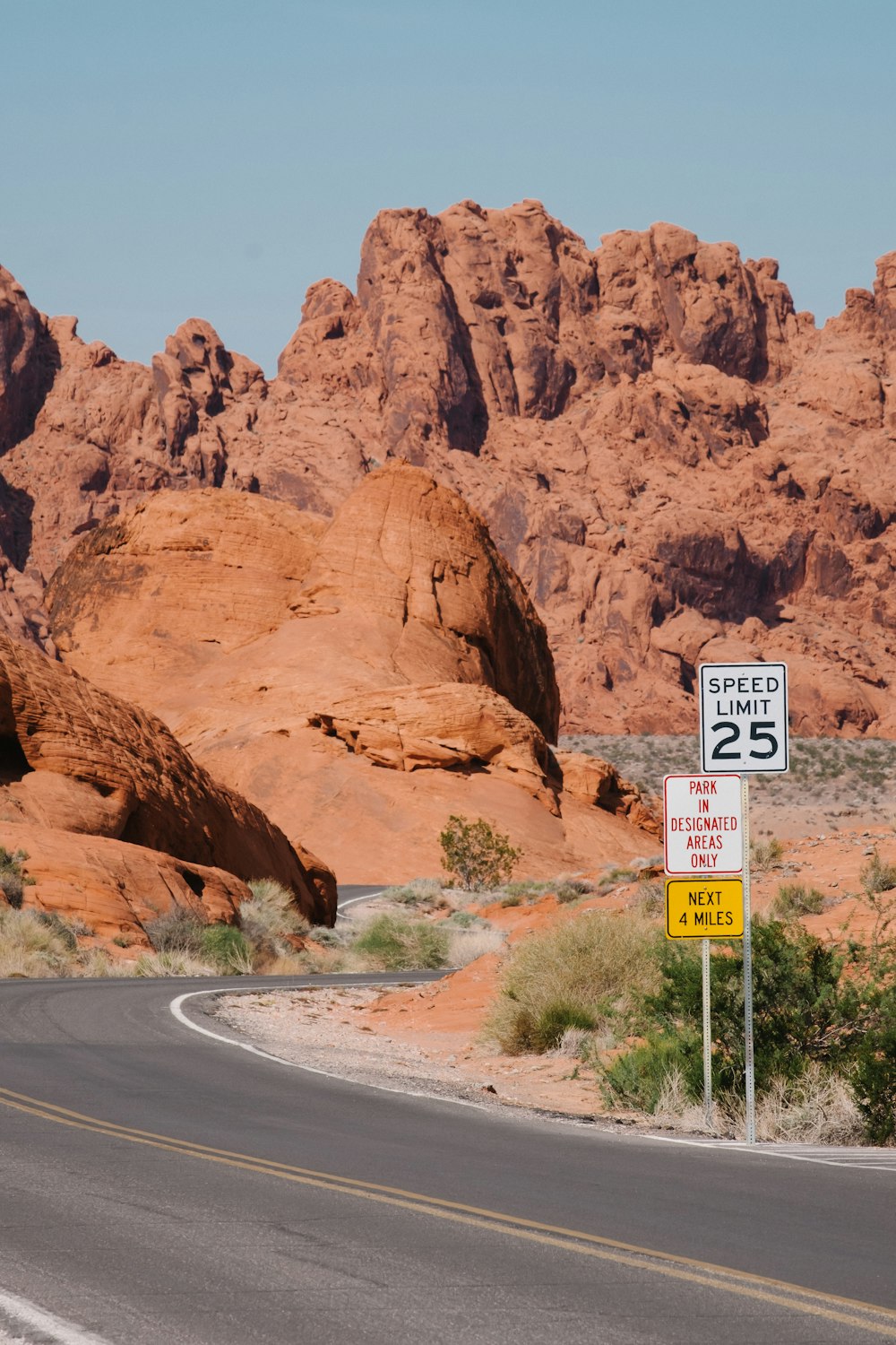 a road with a sign on it and a rocky mountain in the background