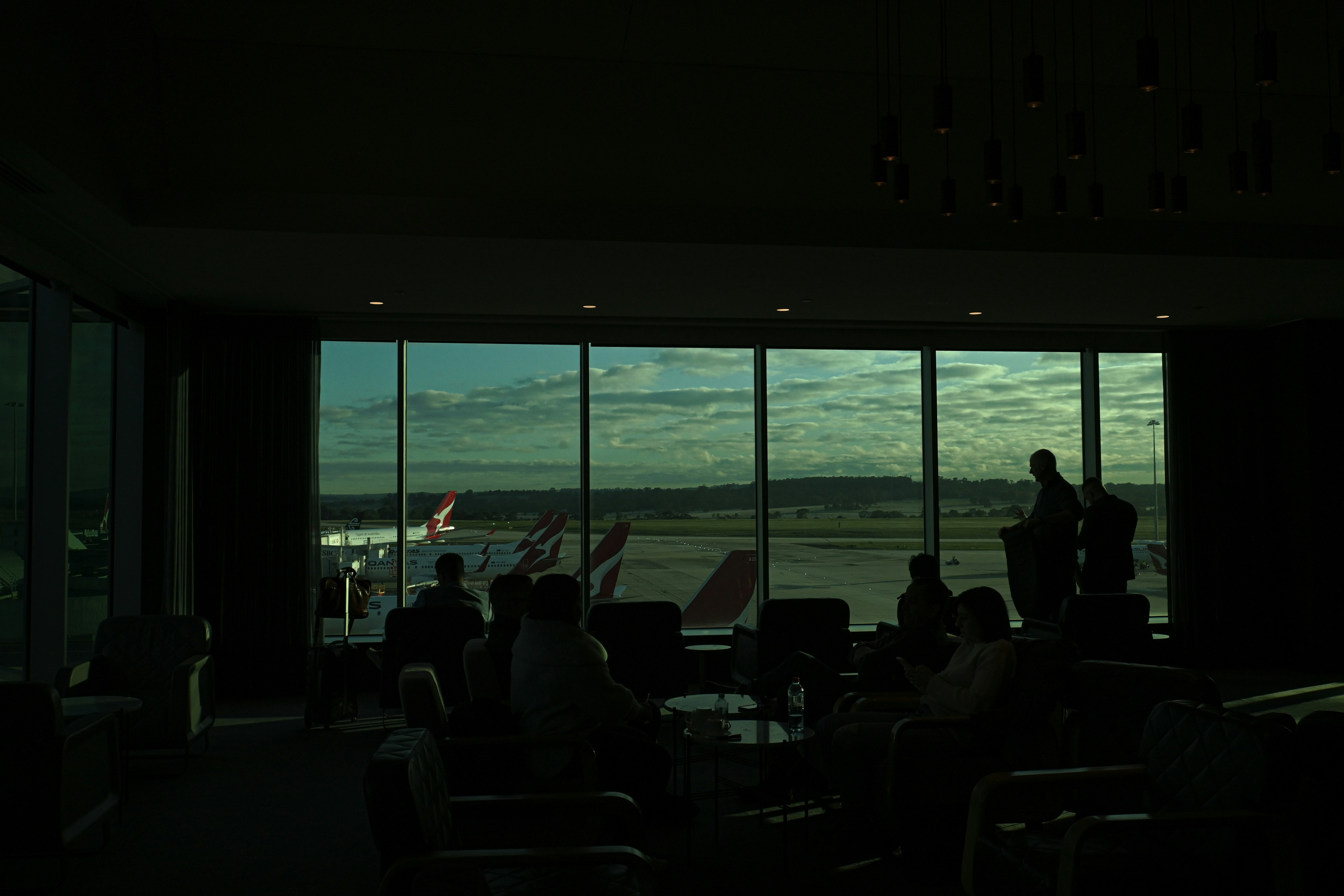 people sitting at tables in a room with large windows looking out to the water, 