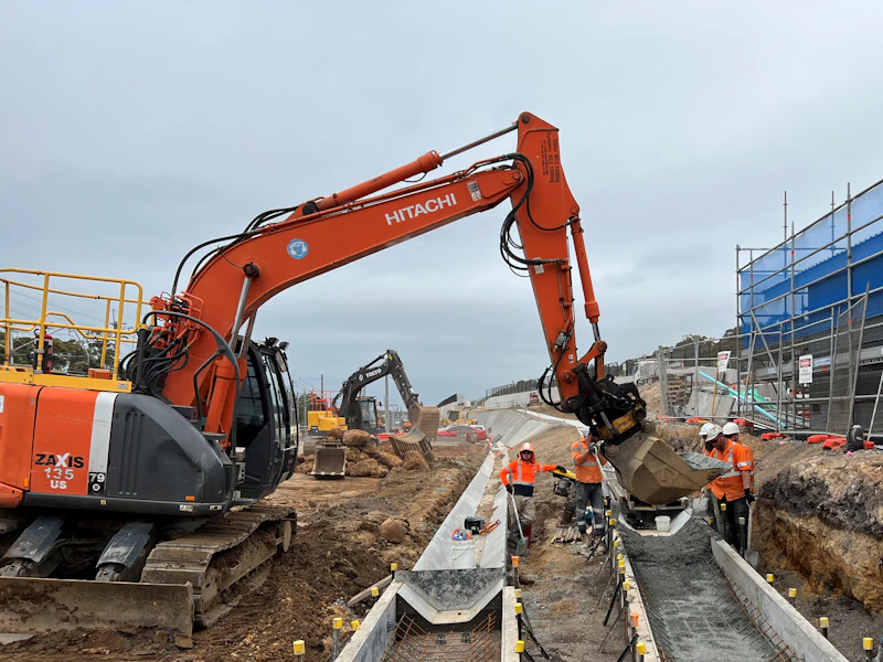 Excavator preparing a site and grading a drain