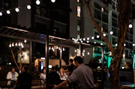 Guests enjoying a lively outdoor dining experience under string lights at dusk.