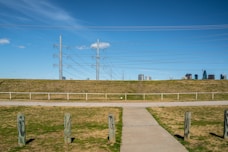 a field with power lines and buildings in the background