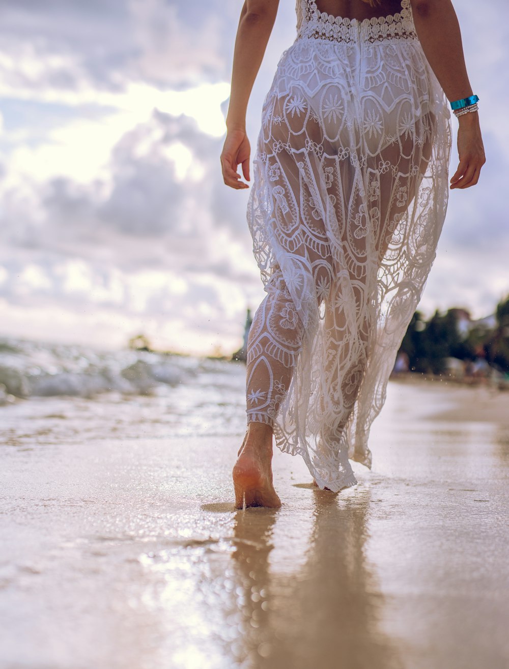 a person wearing a dress walking on a beach