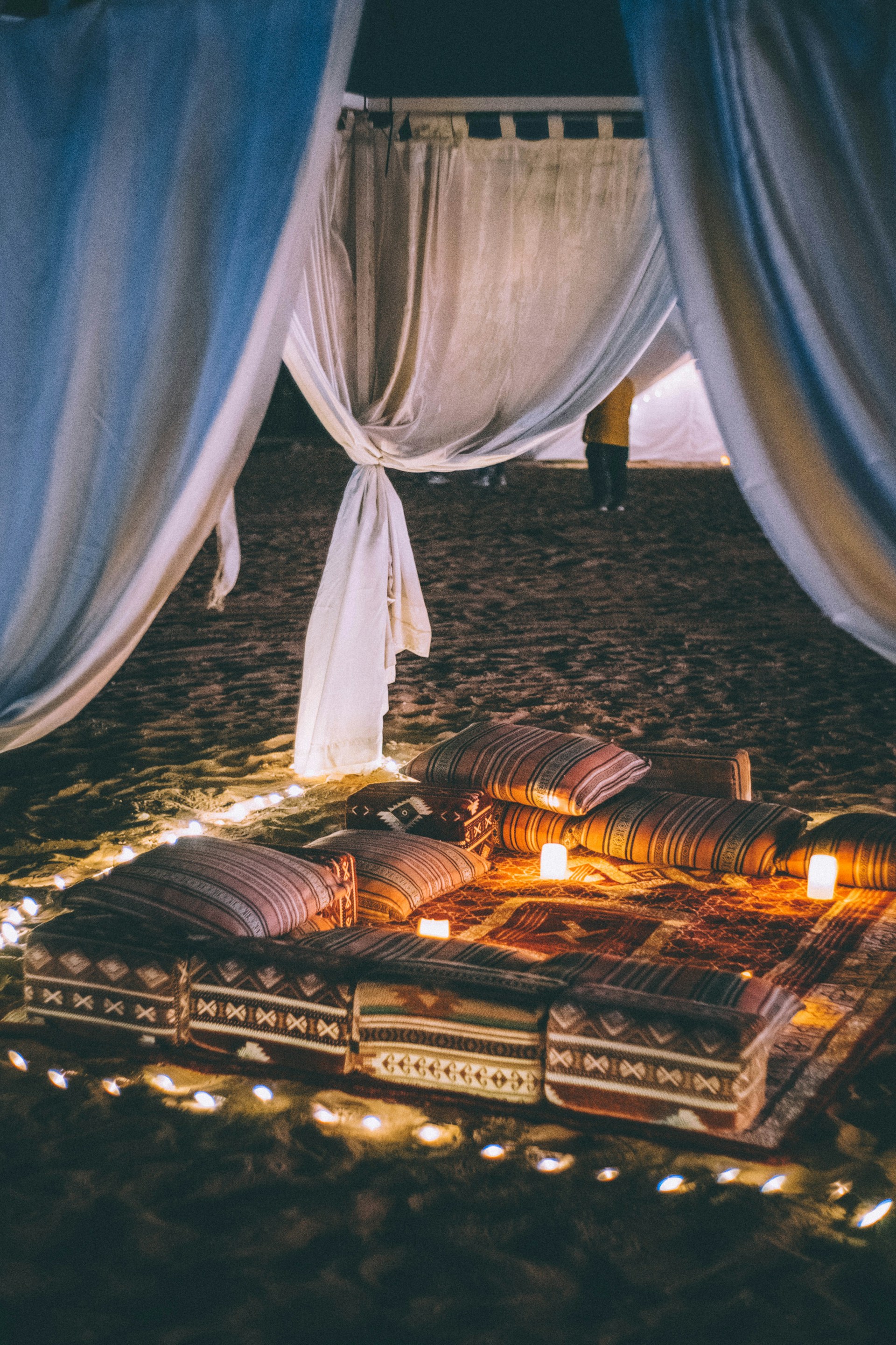 A softly lit Moroccan courtyard adorned with blush and gold lanterns, showcasing an elegant henna night setup with intricate patterns and plush seating.