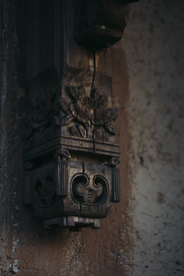 A close-up of a carved wooden wall hanging with intricate details and soft natural lighting.