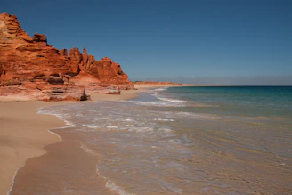 a beach with a cliff and water