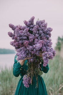 a person holding a bouquet of purple flowers