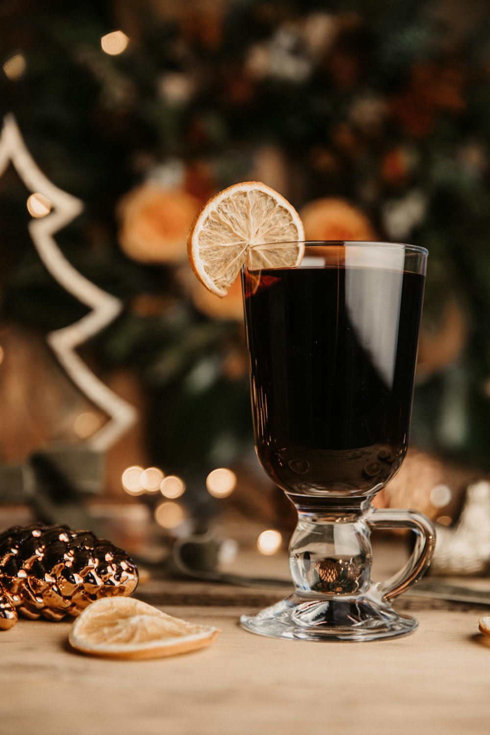 a glass of dark liquid with a slice of lemon on a table