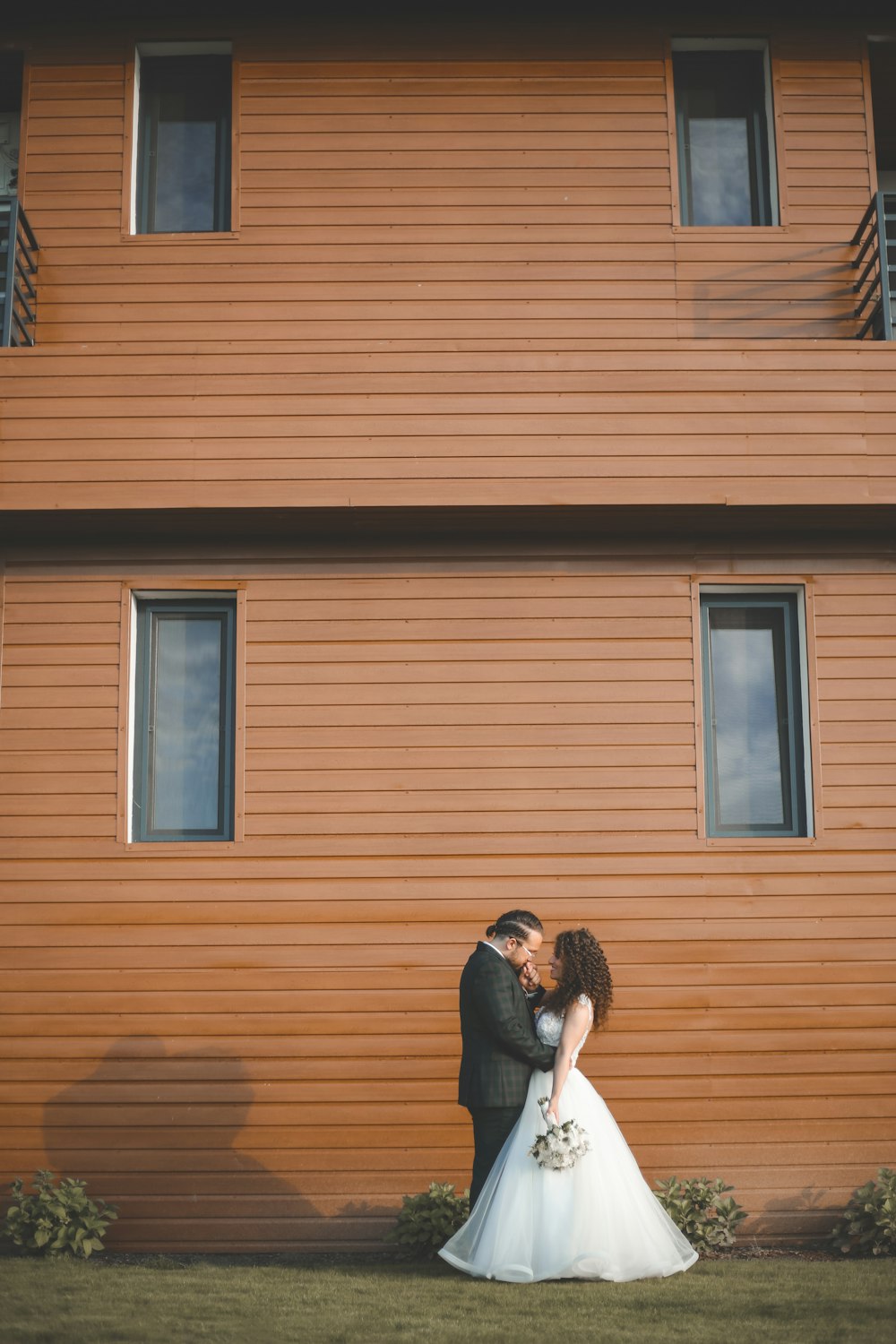 a man and woman kissing in front of a wooden building
