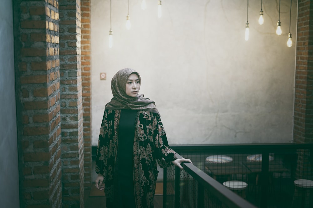 a woman in a green scarf and head scarf standing by a railing