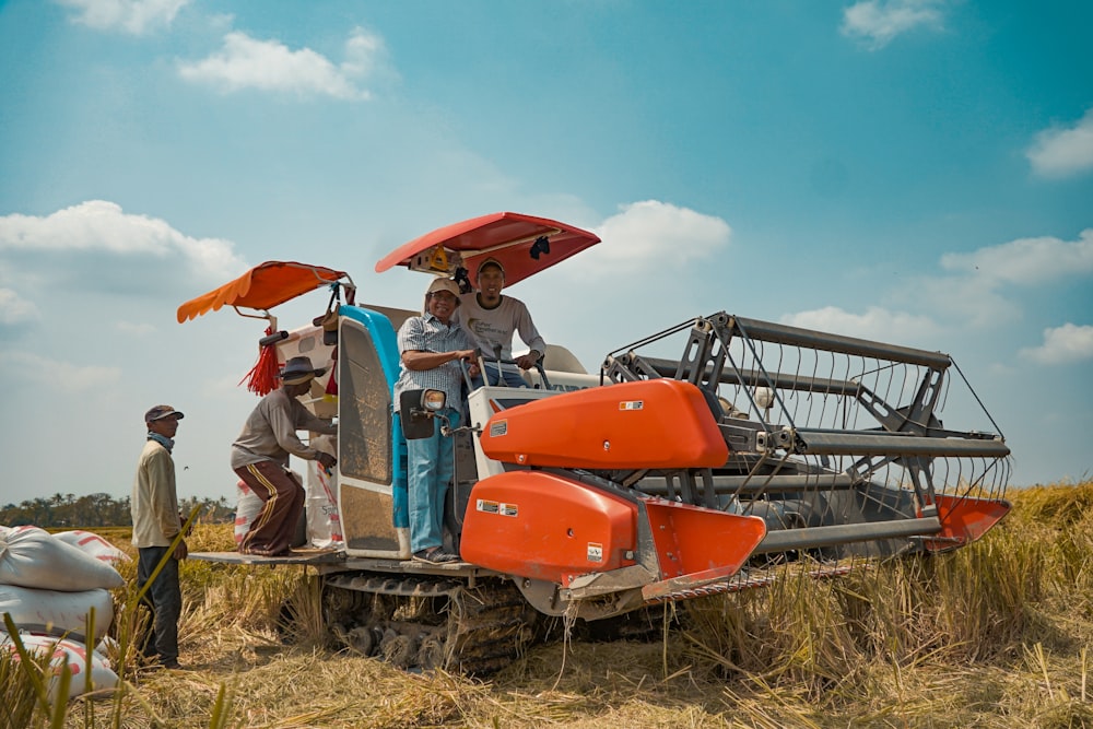 a group of people standing next to a tractor in a field