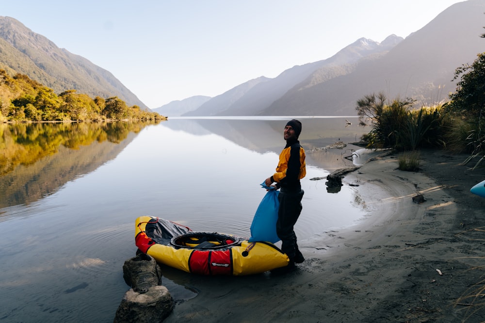 a person standing next to a kayak on a beach