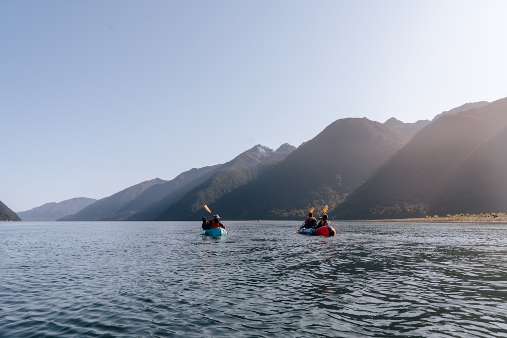 a group of people in kayaks on a lake with mountains in the background