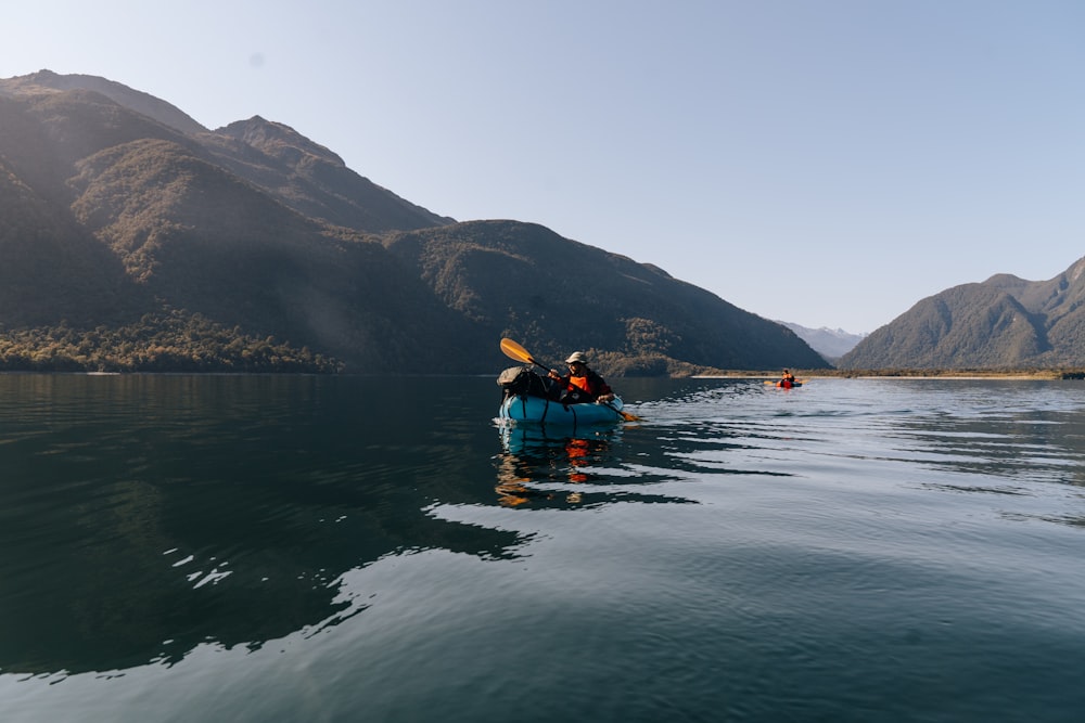 a person in a kayak in a lake with mountains in the background