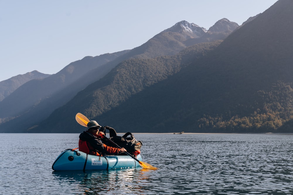 Una persona in un kayak in un lago con le montagne sullo sfondo