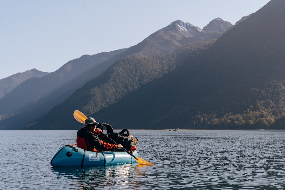 a person in a kayak in a lake with mountains in the background