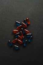 Several translucent capsules in shades of blue and red are scattered on a dark surface.