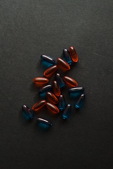 Several translucent capsules in shades of blue and red are scattered on a dark surface.