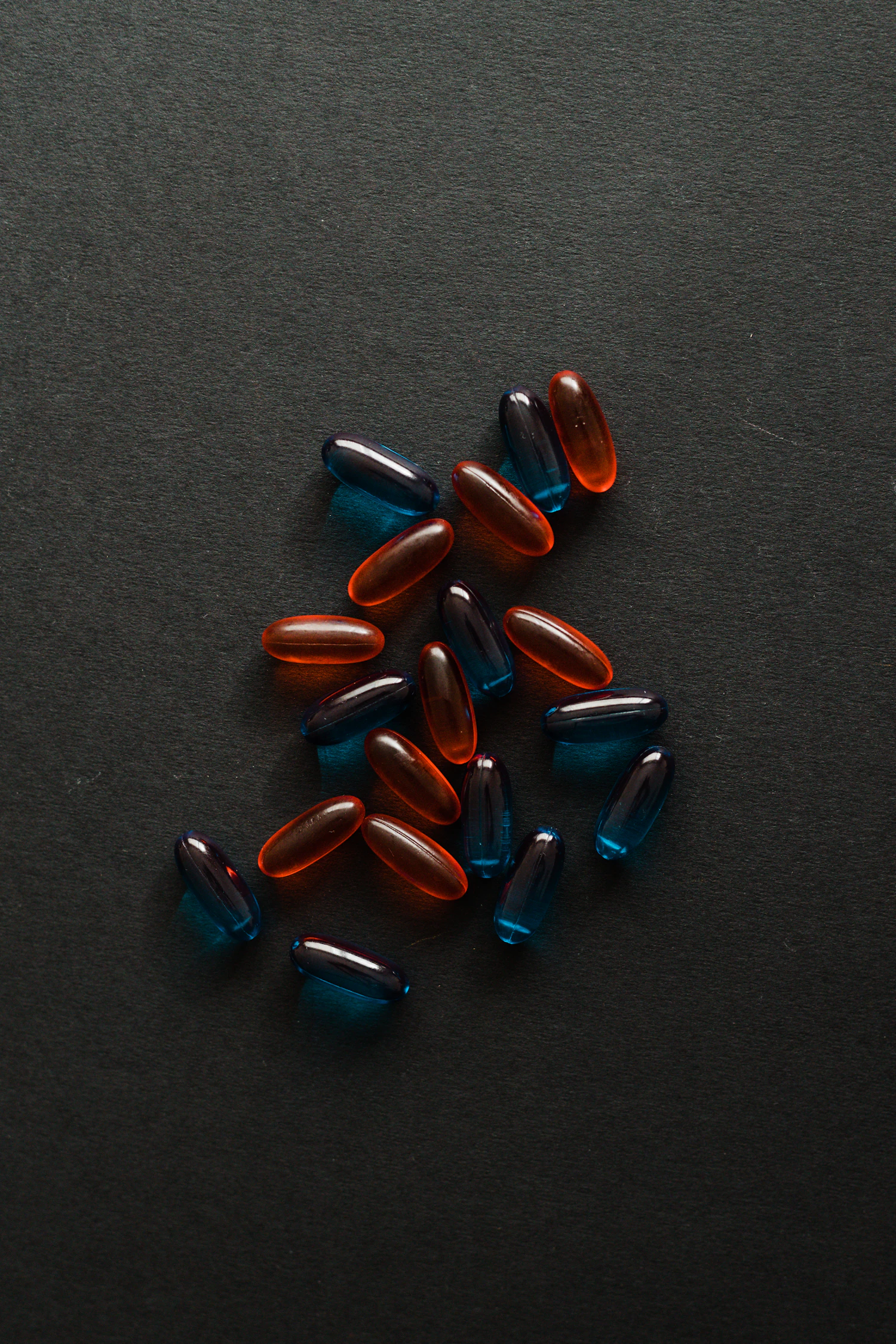 Amber and teal softgels scattered on dark slate