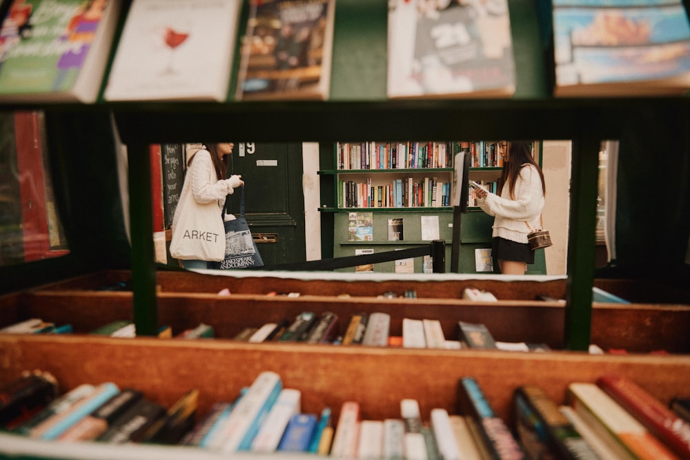 a shelf with books and a couple of women on it