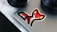 A laptop with a colorful fox sticker on it, positioned on a white wooden surface. Nearby are parts of a camera lens and a circular speaker.