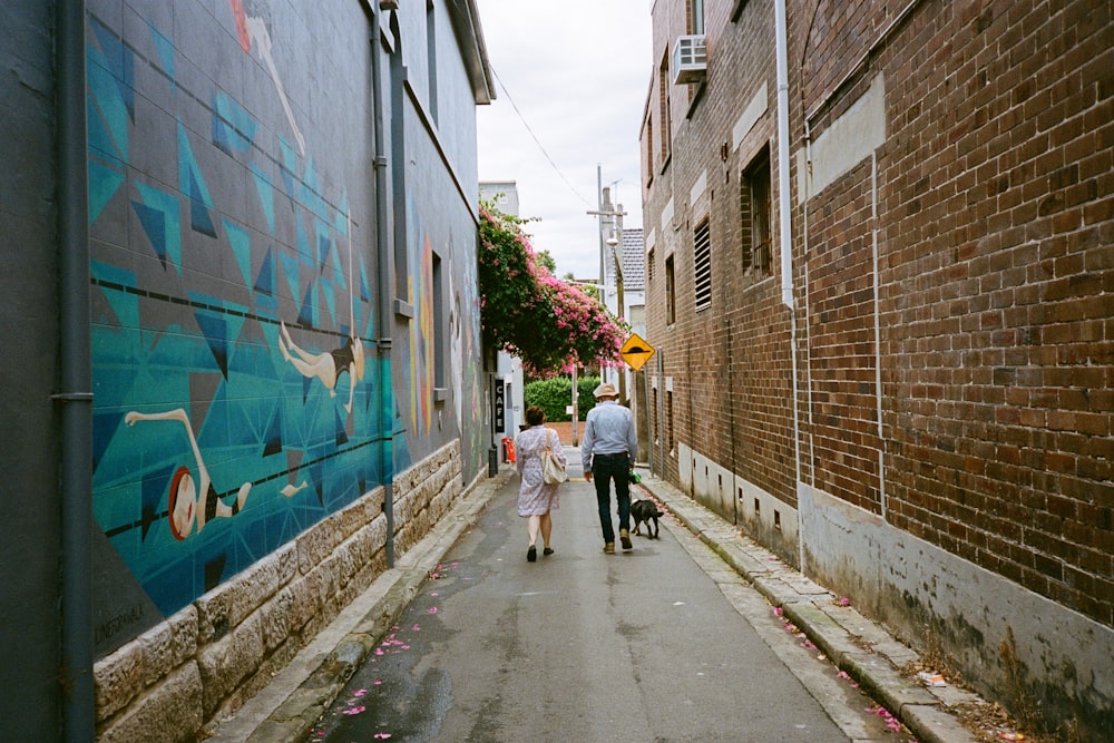 a man and a woman walking a dog down a sidewalk