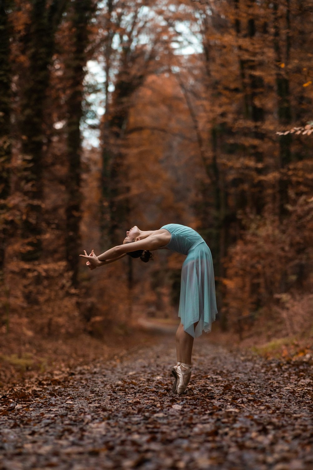 a person in a blue dress dancing in the woods