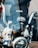 A close-up view of a motorcycle's chrome handlebars and windshield. Behind the windshield, a backpack with the word 'HOOKAH' is visible. The image captures the reflective surfaces and intricate mechanical details of the motorcycle.