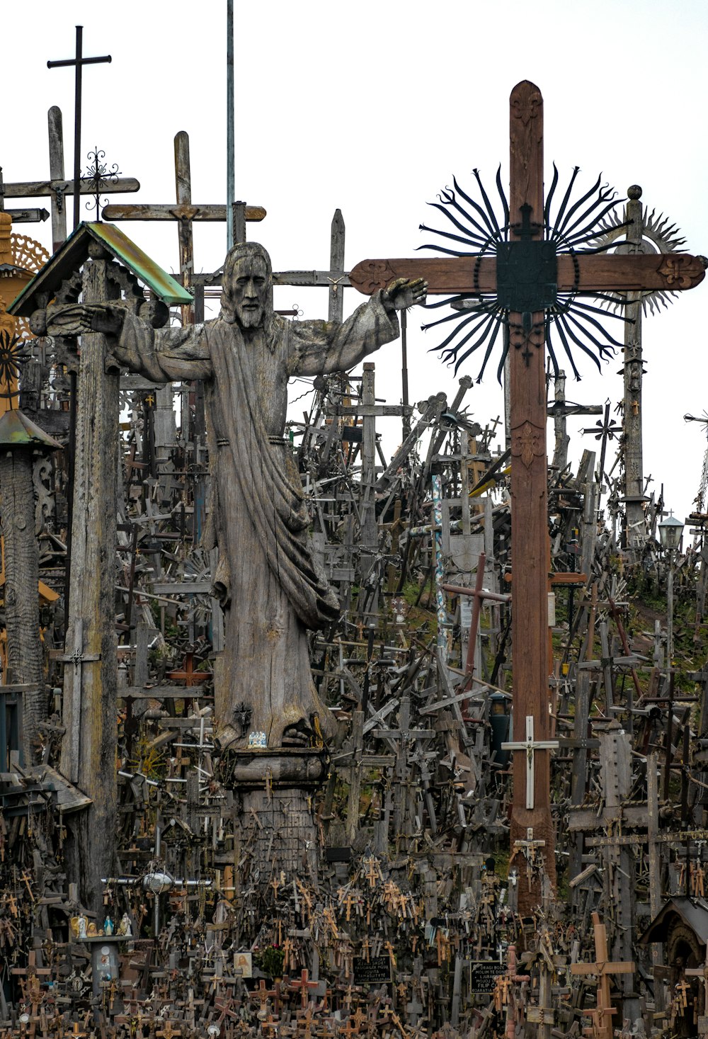 a statue of a person holding a cross in front of Hill of Crosses