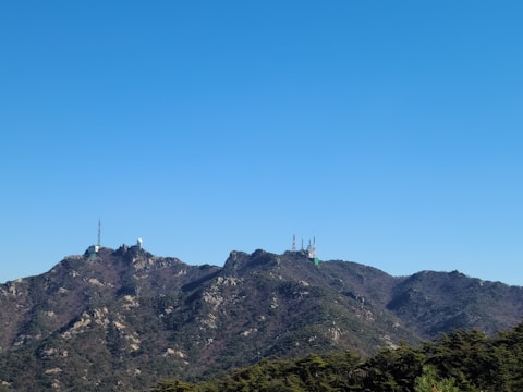 Technicians deploying geophysical equipment in a mountainous area under a clear blue sky.