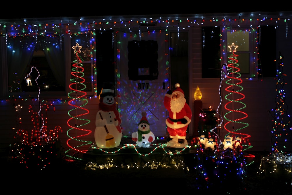 a group of snowman statues in front of a lit up building