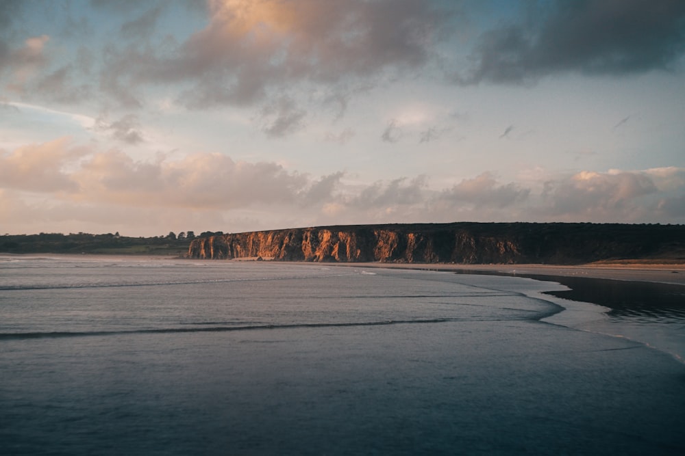 a beach with a large rock formation in the distance