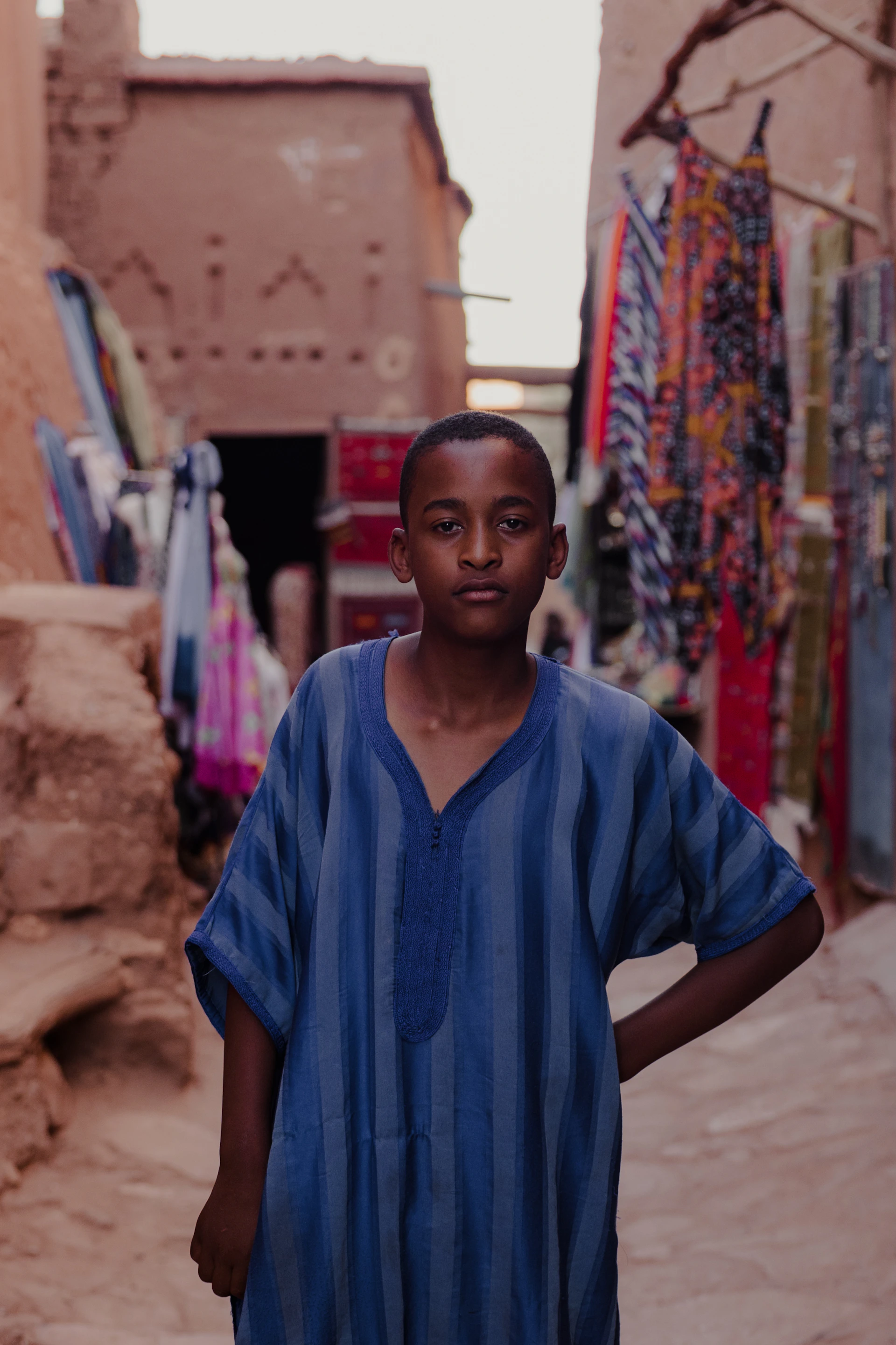 a young boy standing in front of a wall of clothes