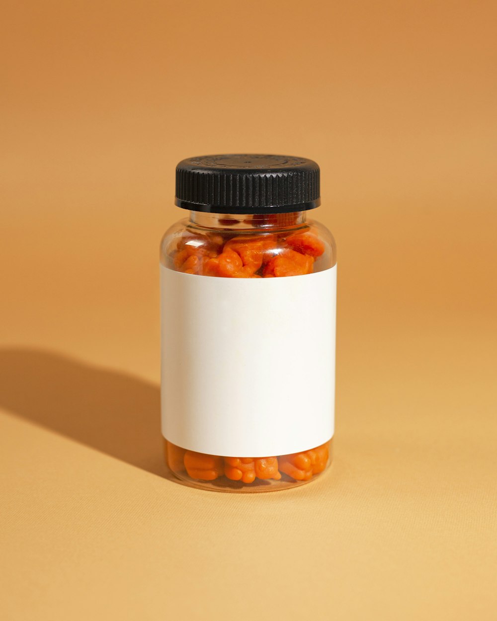 a small glass jar with a black lid and a black cap