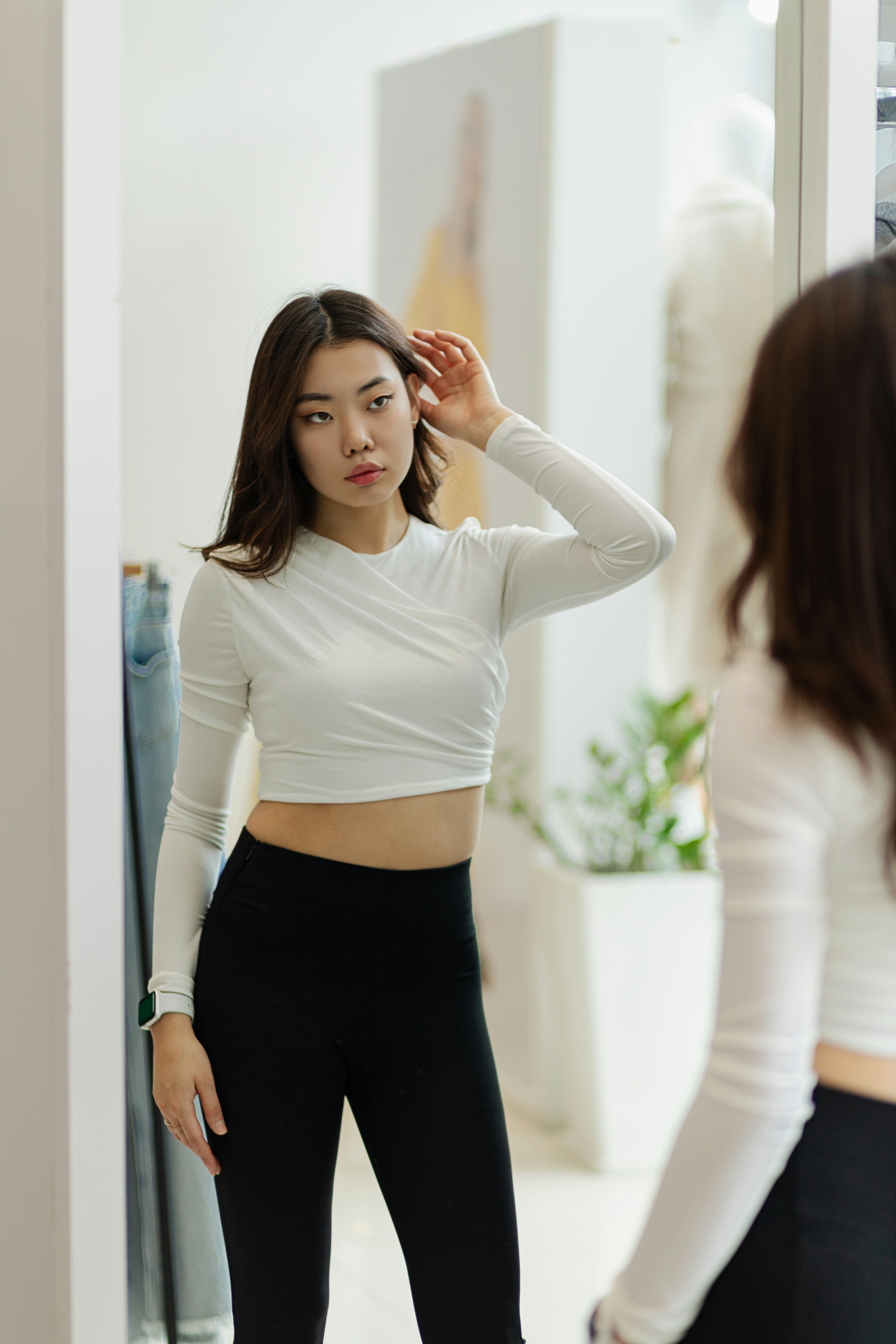 Woman in workout clothes adjusting her hair in a mirror.