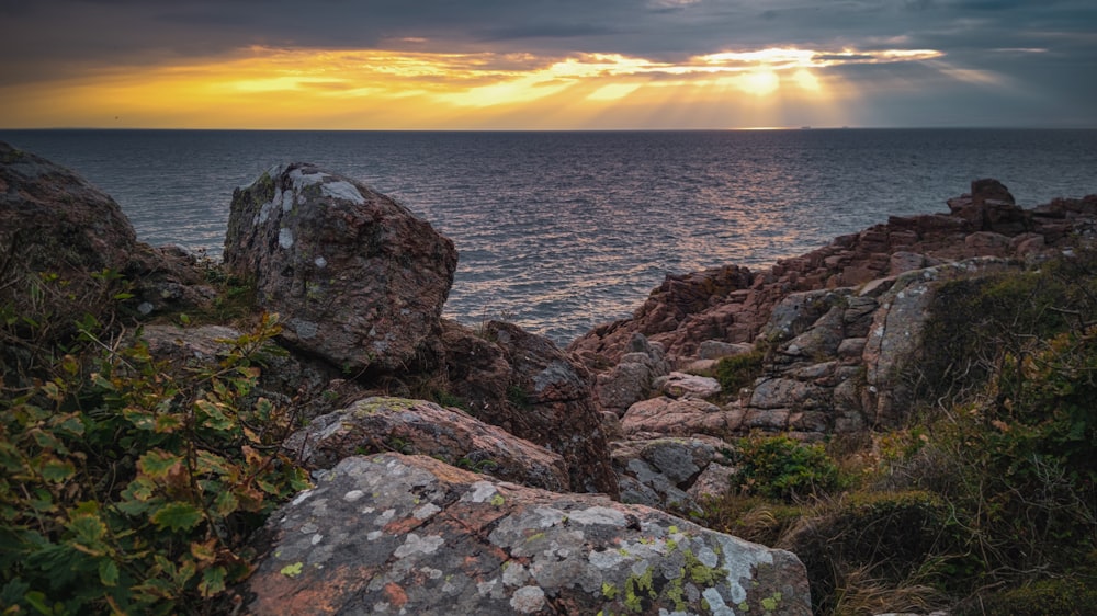 a rocky shoreline with a sunset