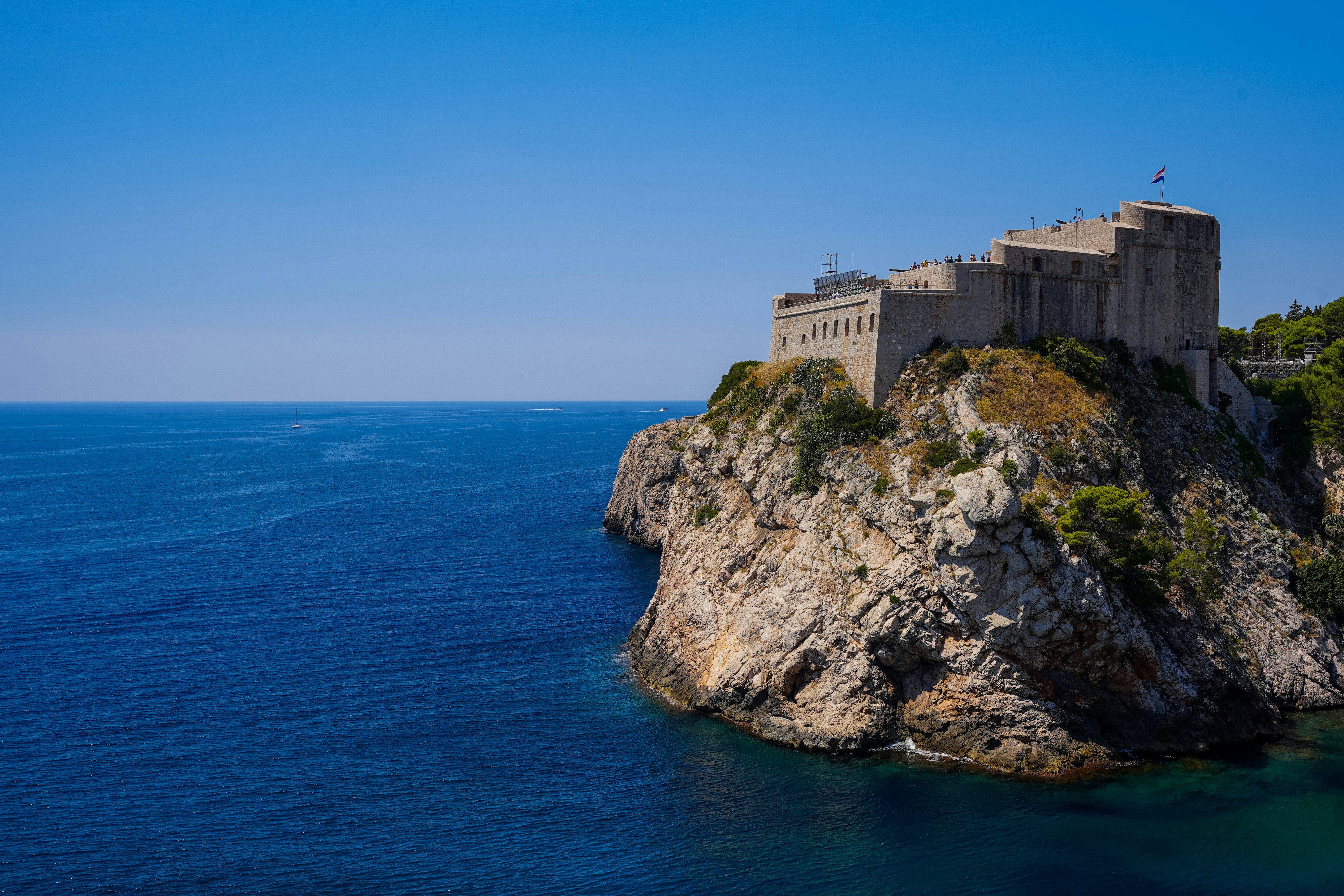 A castle on a cliff over the ocean with lovrijenac in the background
