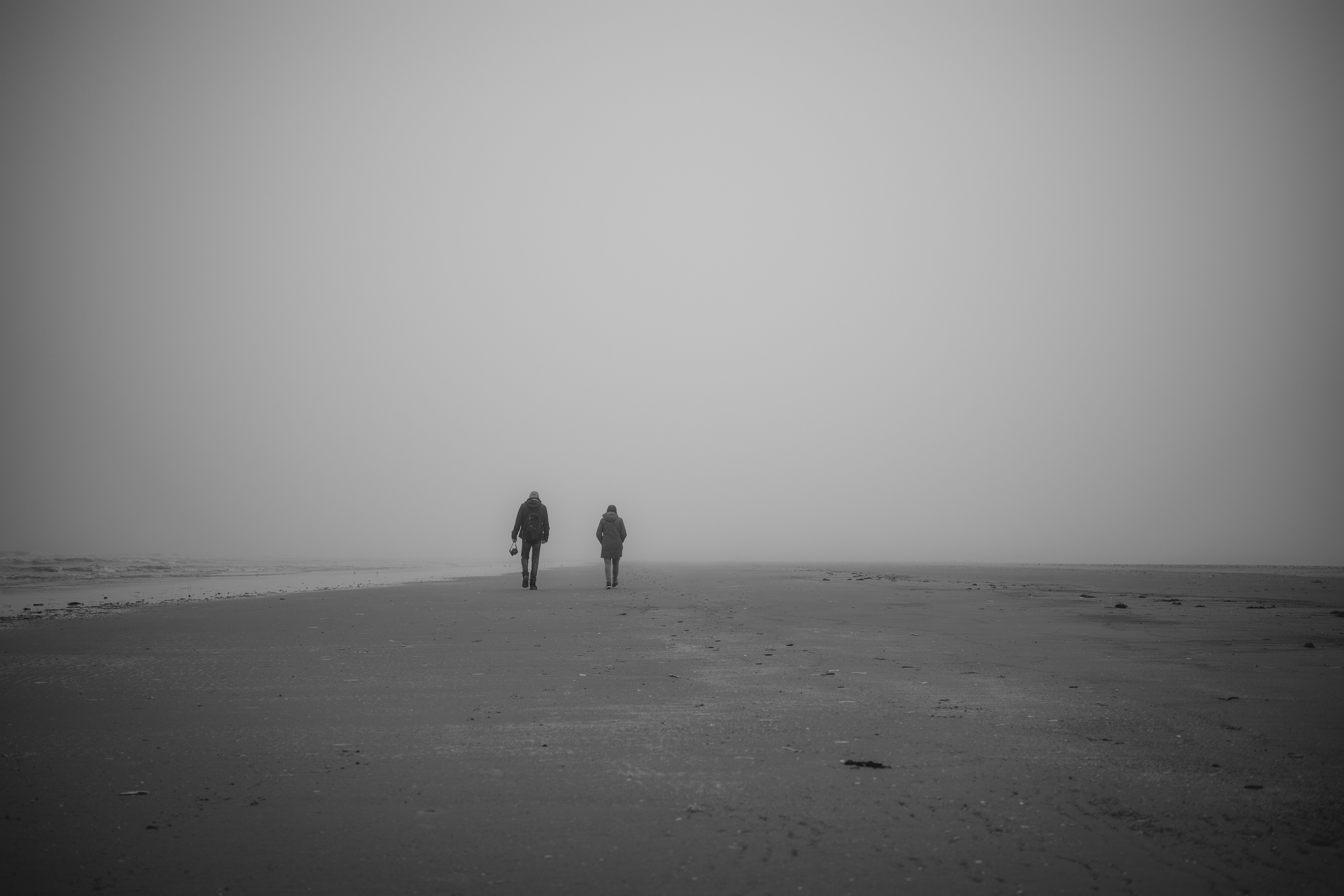two people walking on a beach