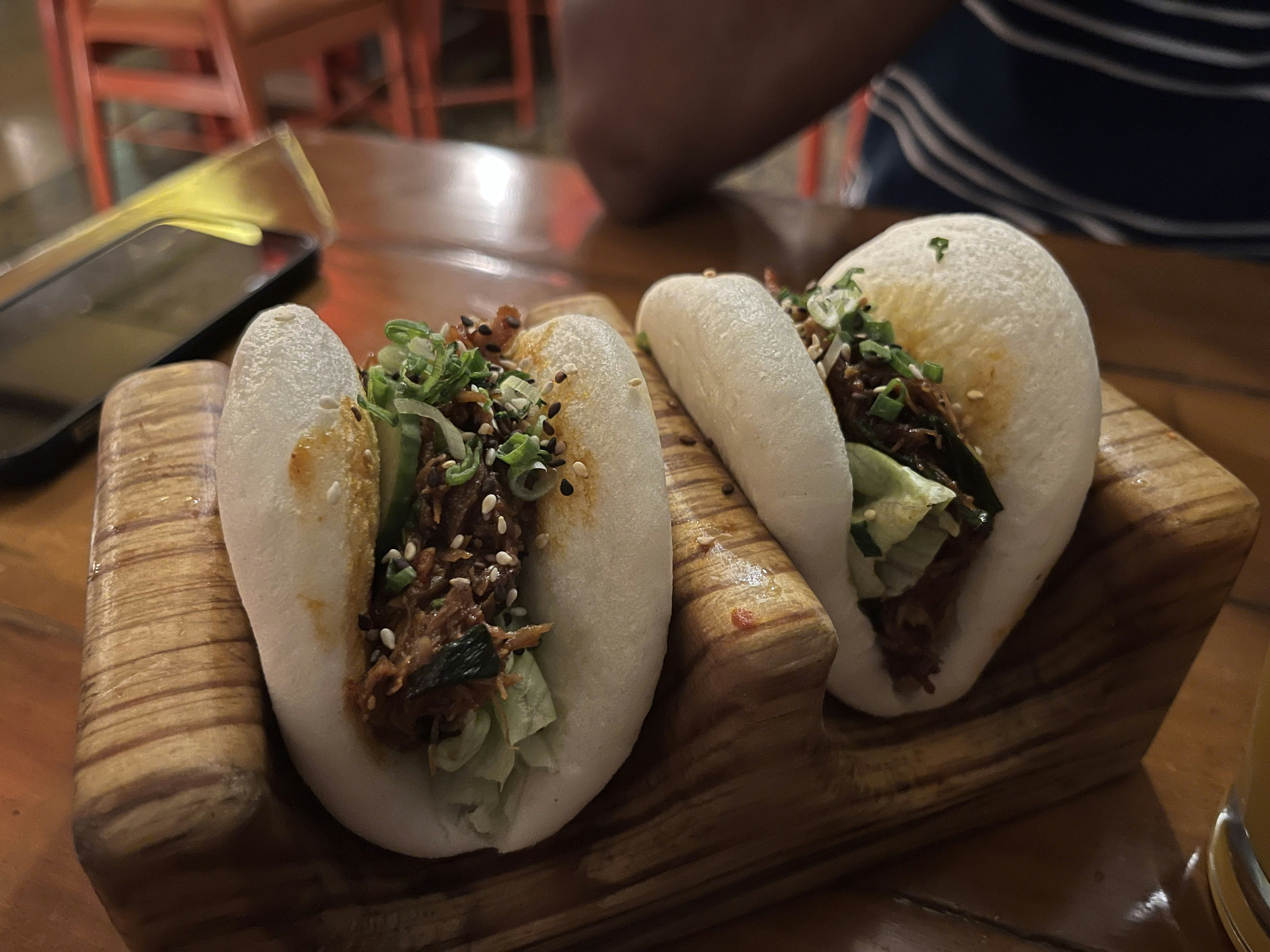 Two filled bao buns on a wooden board